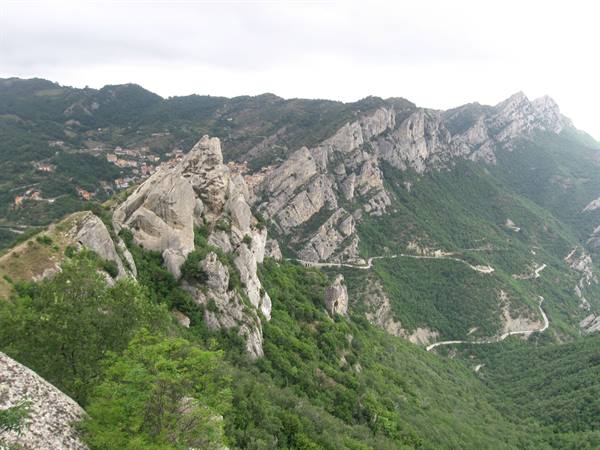 limestone rocks above a village, winding road through the green valley