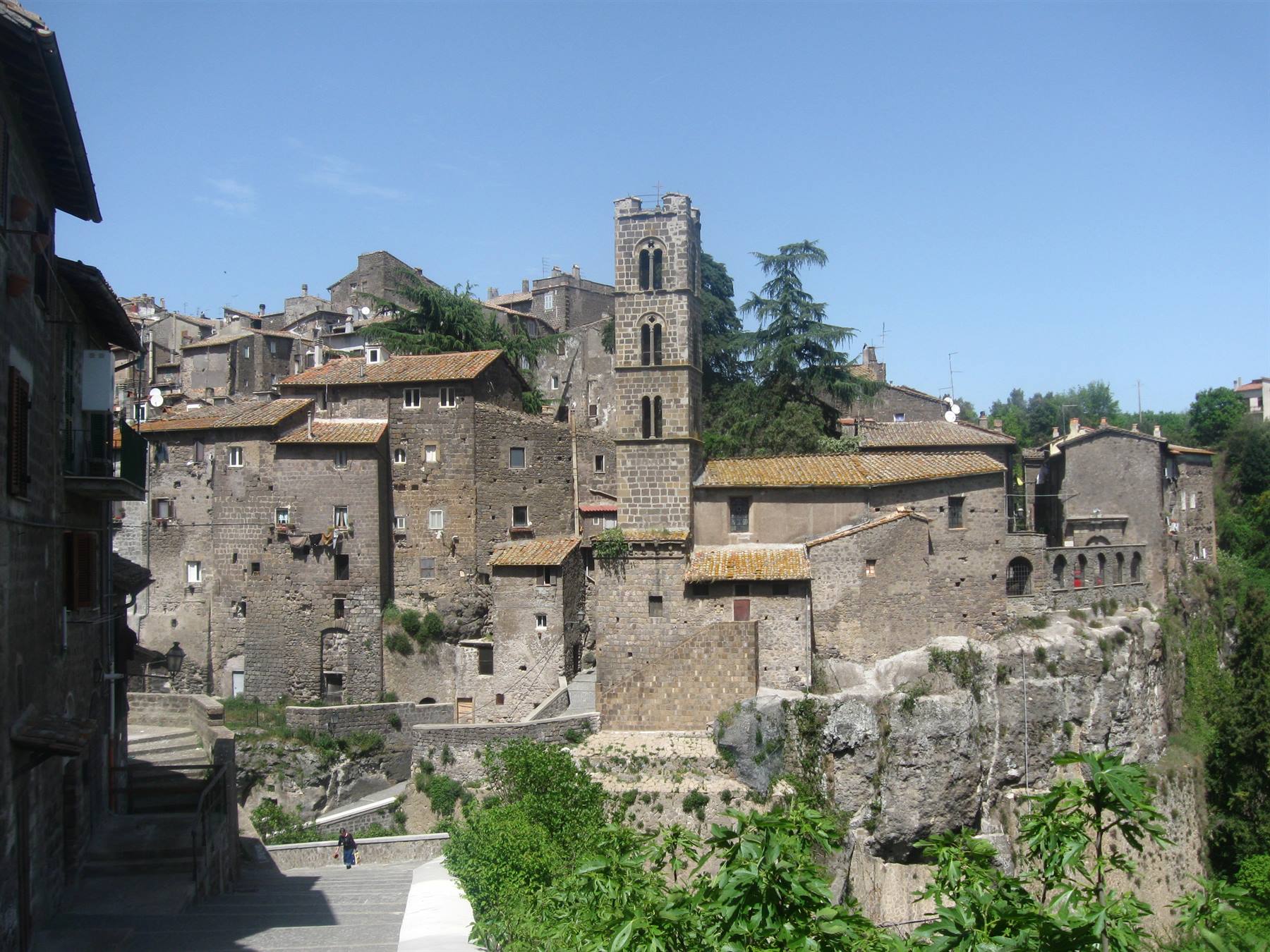 Vitorchiano: case di tufo su Rocca, campanile romanico, scalinata sotto cielo azzurro