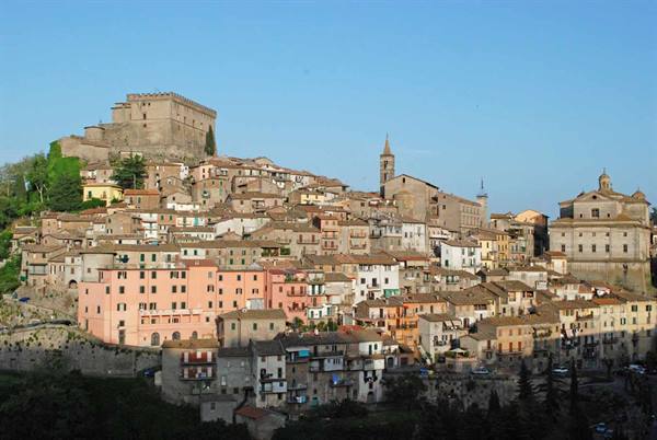 Hilltop stone town with castle and churches under clear blue sky
