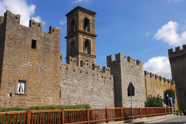 Medieval stone walls with battlements and bell tower, Viterbo, under blue sky