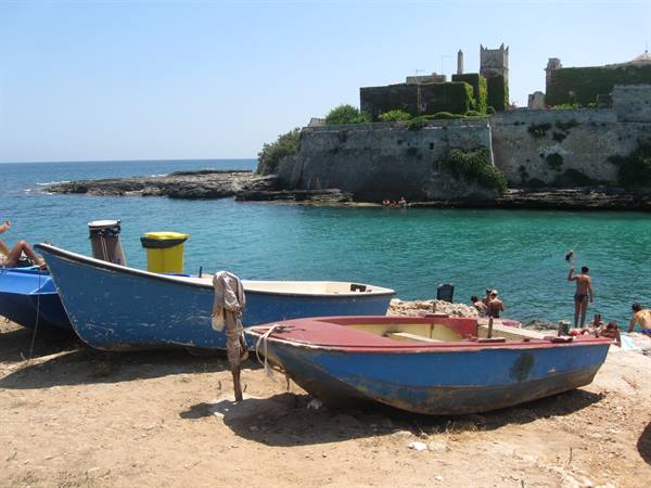 Blue wooden boats on the beach in front of Pianosa fortress
