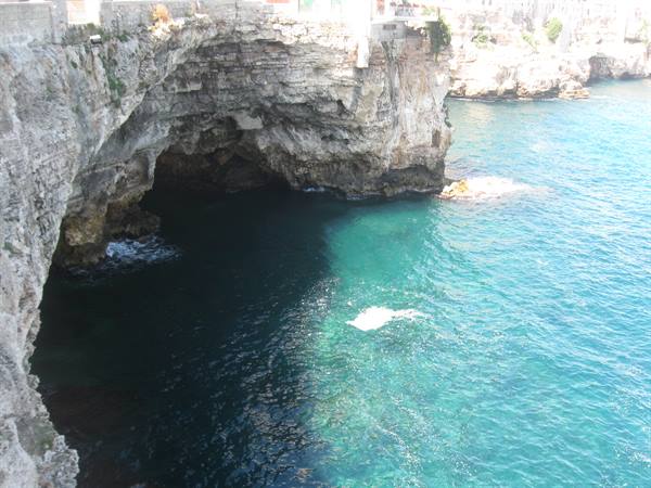 Limestone cliff with cave over turquoise sea in Polignano a Mare, sunlight