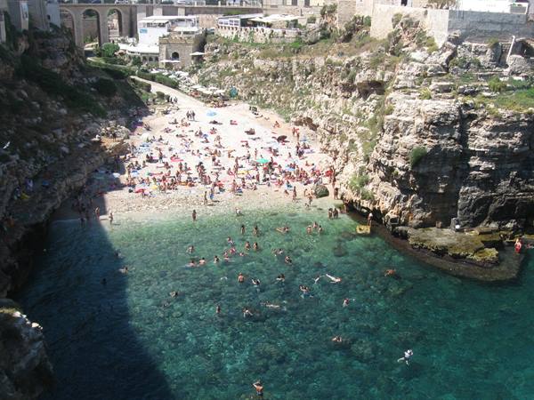 Swimmers at Lama Monachile cove in Polignano a Mare, limestone cliffs and turquoise water