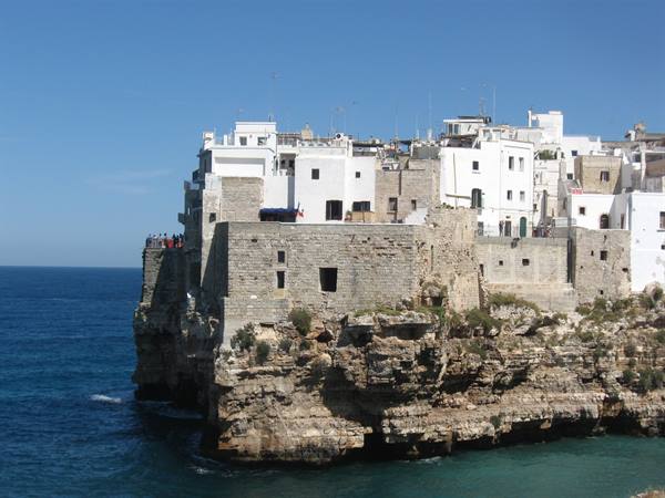 White houses on limestone cliffs in Polignano a Mare, clear sky and blue sea