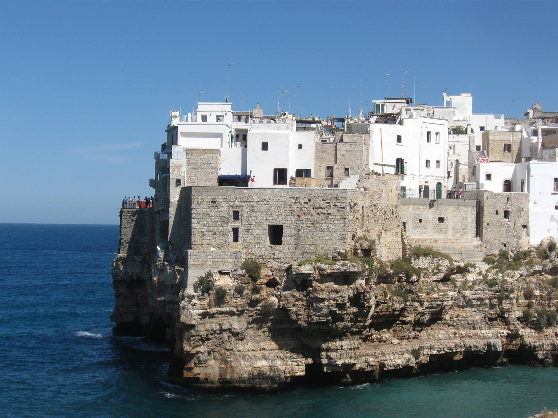 Case bianche su scogliera calcarea a Polignano a Mare, cielo sereno e mare blu