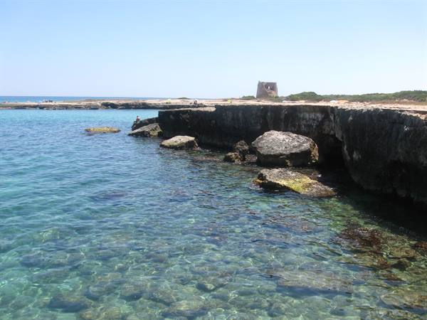 Clear turquoise water over limestone rocks, ancient tower on the coast