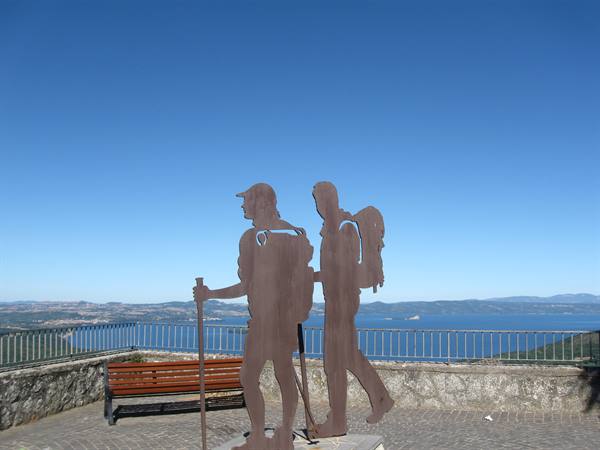 Iron sculpture of two hikers on a terrace above the lake