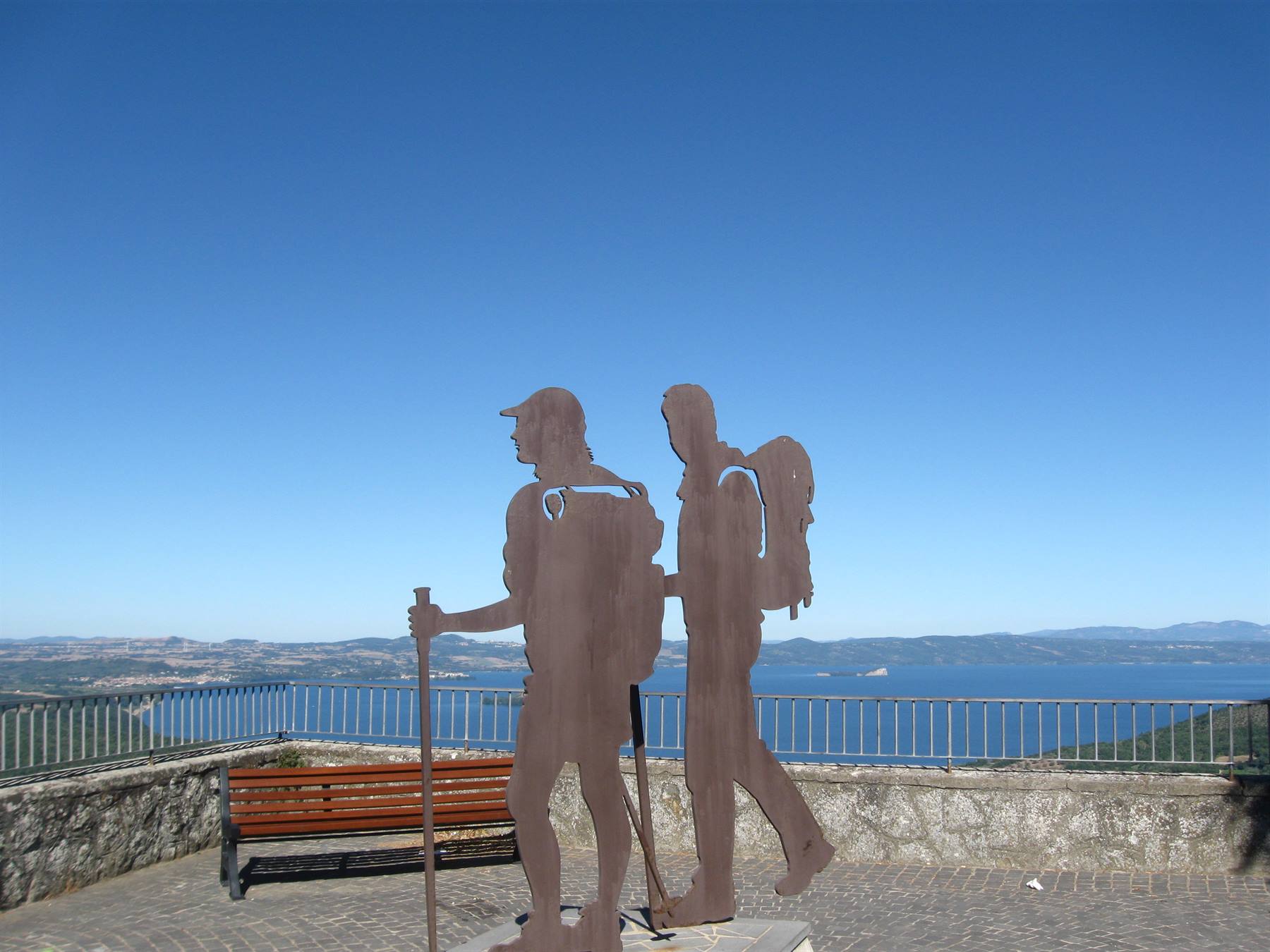 Scultura in ferro di due escursionisti su terrazza sopra il lago