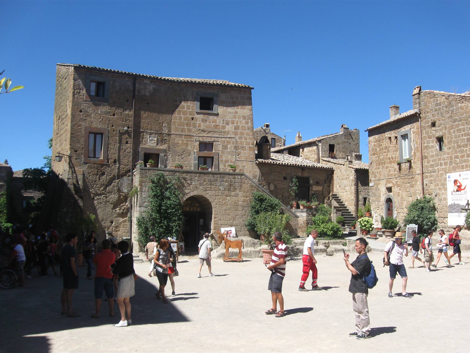 Turisti nella piazza di Civita di Bagnoregio tra case in tufo