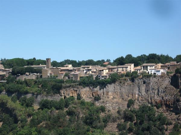 Stone houses and bell tower on the edge of a sunny tuff cliff