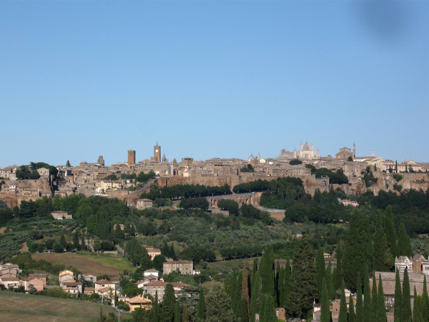 Orvieto: case di tufo sulla collina, cattedrale e torri tra cipressi verdi