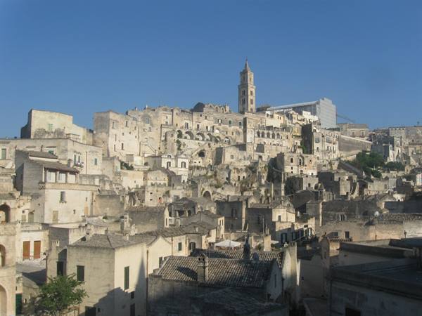 Matera's Sassi: stacked limestone houses, Romanesque bell tower, clear blue sky