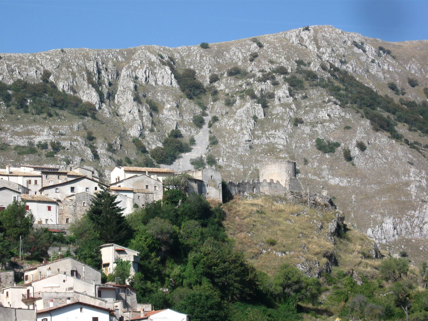 Borgo di case in pietra sotto la montagna rocciosa, torre medievale in mezzo