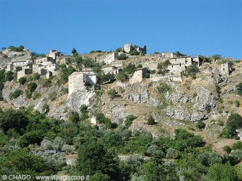 Abandoned stone houses clustered on rocky hillside beneath clear blue sky