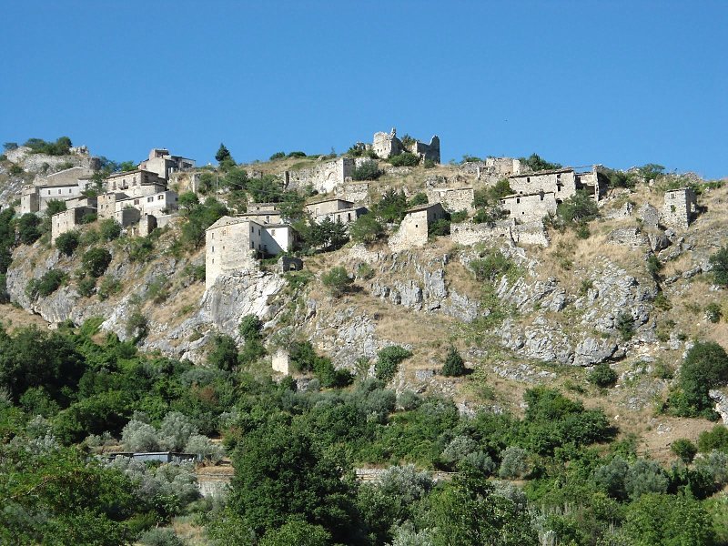 Borgo abbandonato di case in pietra sulla roccia sotto cielo azzurro