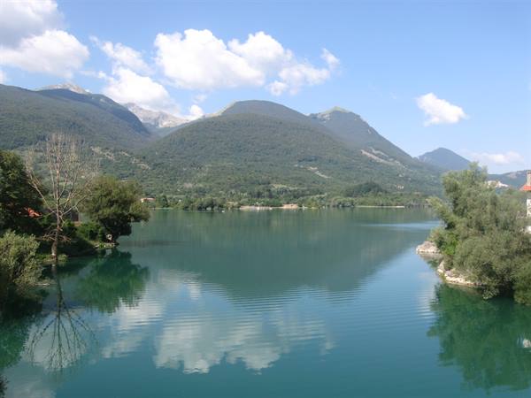 Lake Barrea, green water framed by trees and green mountains, cloudy sky