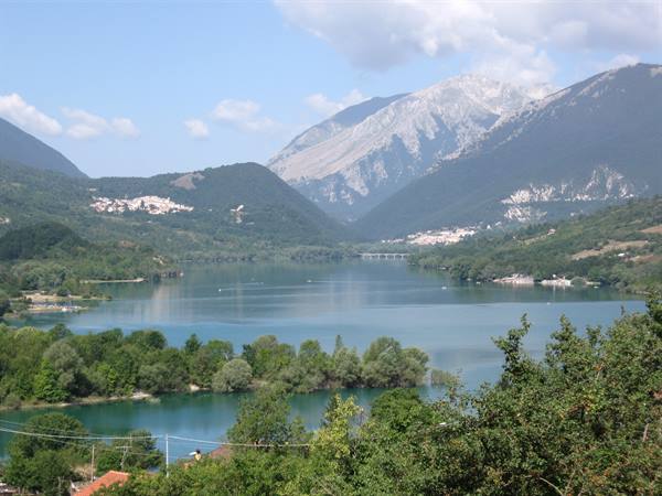 Barrea Lake with turquoise water surrounded by woods and Apennine peaks, villages along the shore