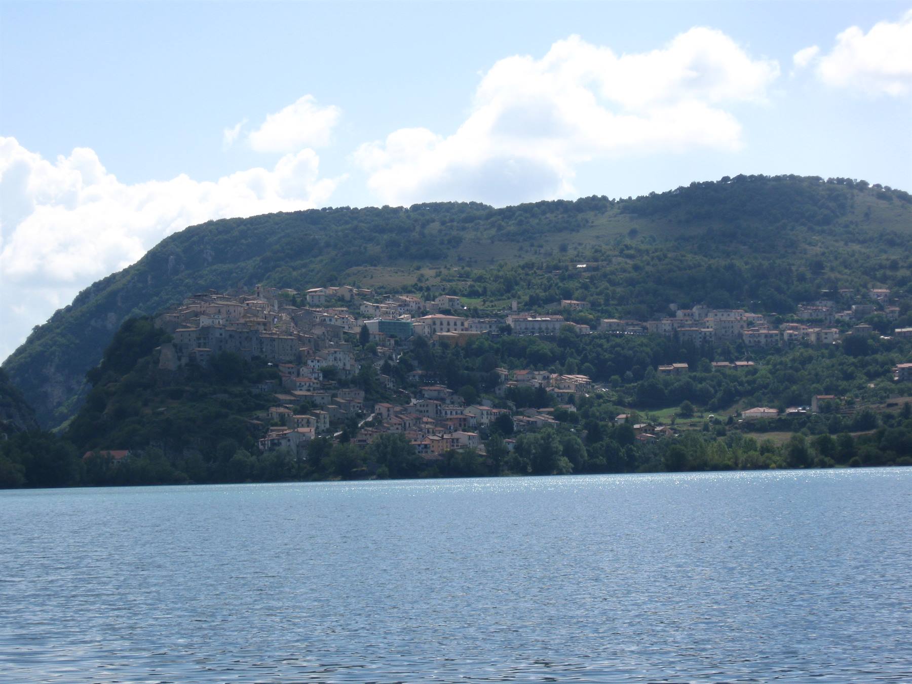 Borgo di case addossato alla montagna verde sulle rive del lago di Piediluco