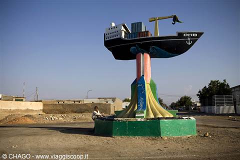 Cargo ship monument on a painted column, a man sitting nearby