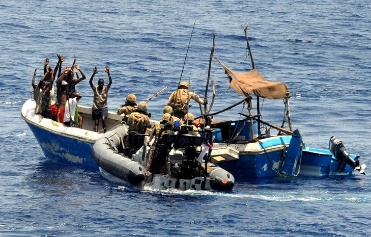 Soldati con gilet tattico su gommone accostano pescatori su barca blu