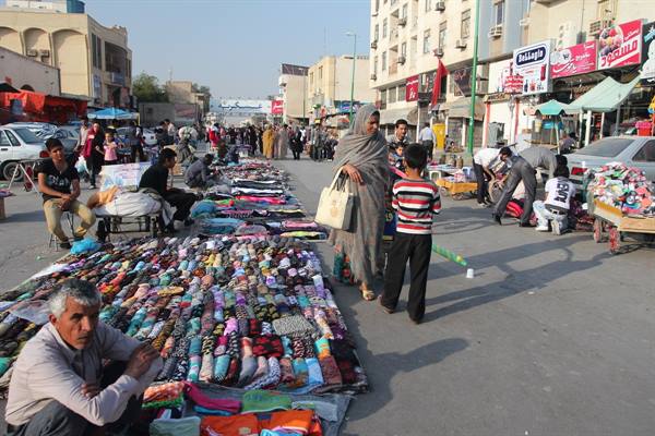 Street market: vendors display colorful fabrics on the ground among city buildings
