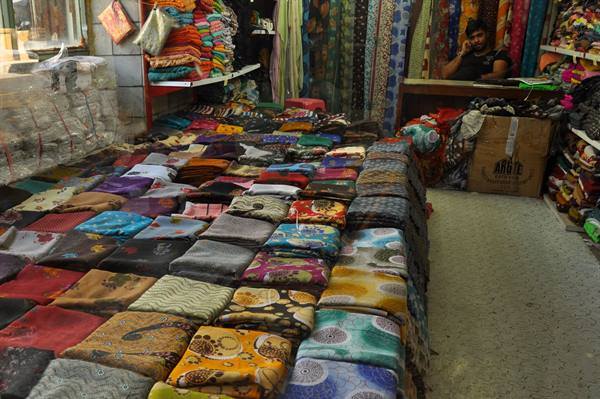 Fabric shop with folded colorful textiles on counters and clerk on phone