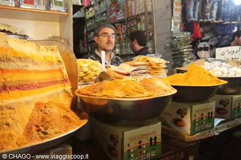 Spice vendor at market stall, metal bowls filled with turmeric and chili powder