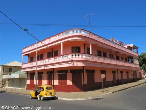 Yellow taxi parked in front of a pink colonial corner building