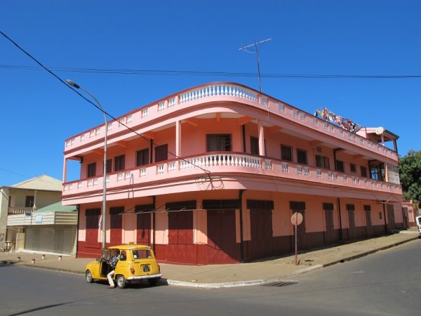 Taxi giallo parcheggiato davanti a un palazzo coloniale rosa angolare