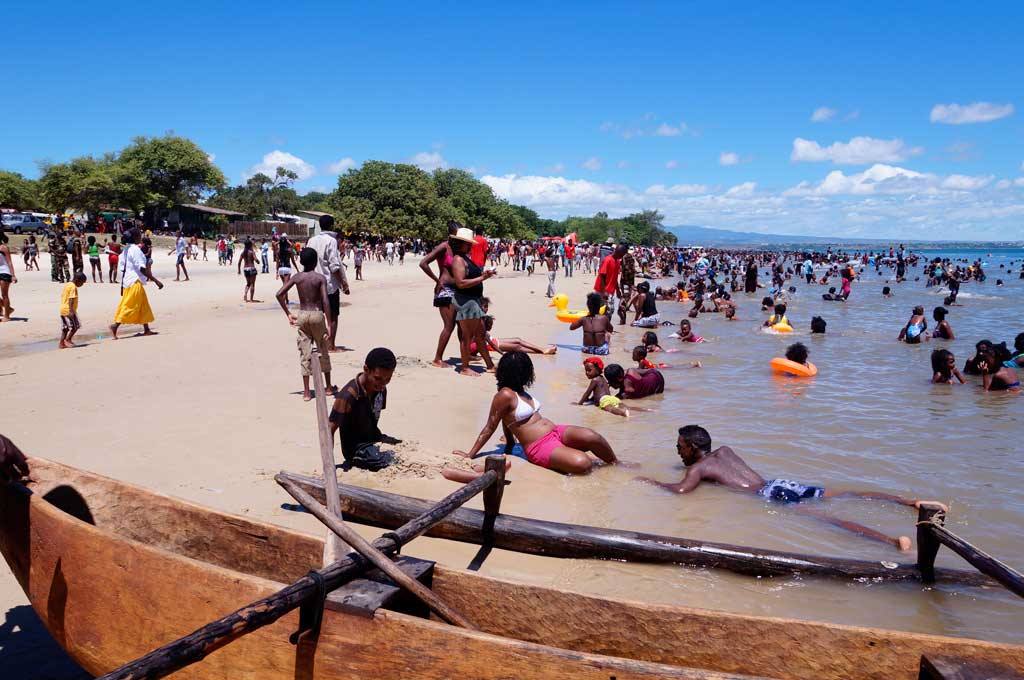 Bagnanti sulla sabbia accanto a una piroga di legno, spiaggia affollata sotto il sole