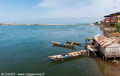Wooden pirogues moored beside corrugated iron shacks on stilts