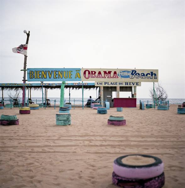 Obama Beach bar on sand, painted sign, colorful tire seats under grey sky
