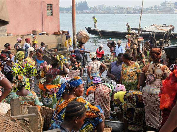 Women in colorful clothes with baskets at Elmina harbor fish market