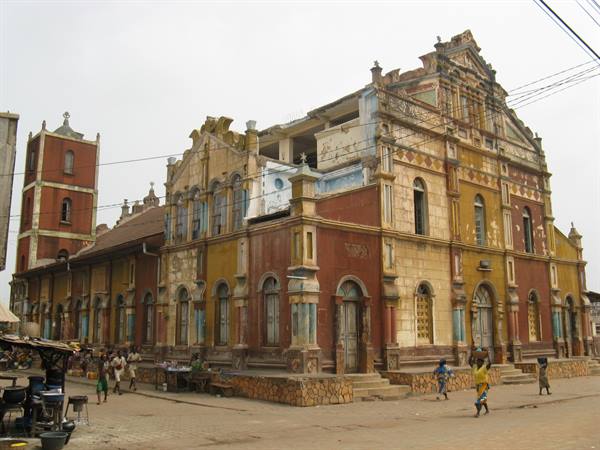 Colonial ochre brick church with bell tower, people walking on the street