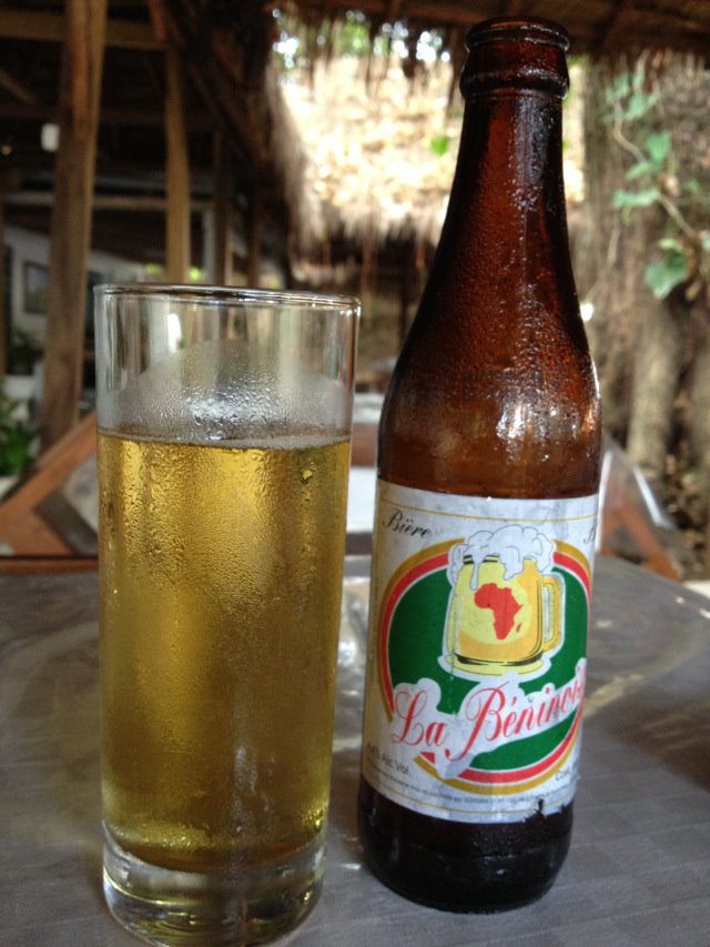 Bottige di birra La Beninoise e bicchiere pieno su tavolo all'aperto