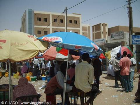 Street market with colorful umbrellas and Arabic signs between buildings