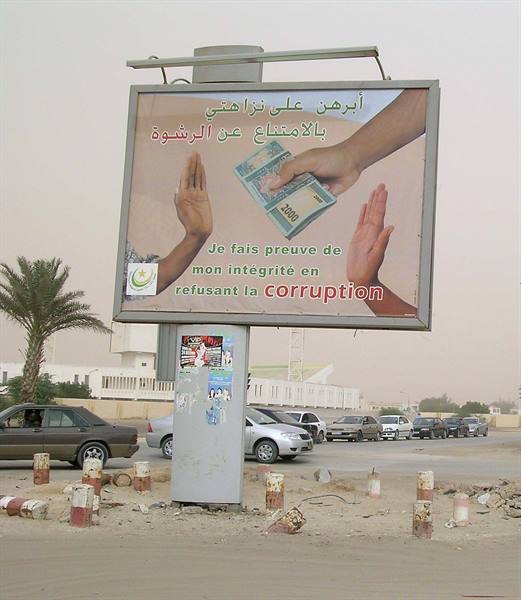 Anticorruption billboard with hands refusing banknotes, palm trees and parked cars