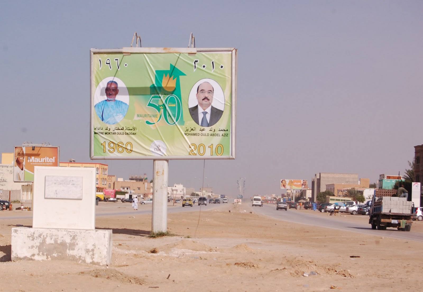 Cartellone stradale per i 50 anni dell'indipendenza, sabbia e traffico, Mauritania