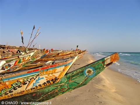 Colorful painted wooden pirogues lined up on the sandy beach