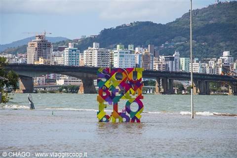 Colorful SOU FLORIPA sculpture in the water in front of Hercílio Luz bridge