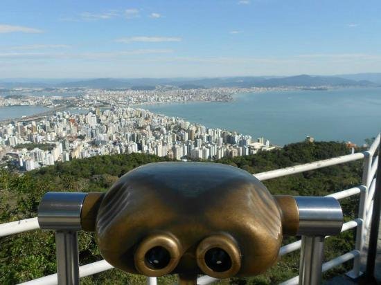 Cannocchiale metallico su terrazza panoramica davanti a città e baia azzurra