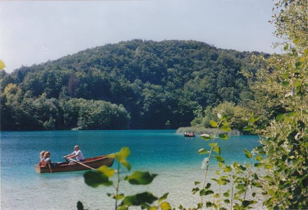 Wooden rowboat with tourists on the turquoise lakes of Plitvice