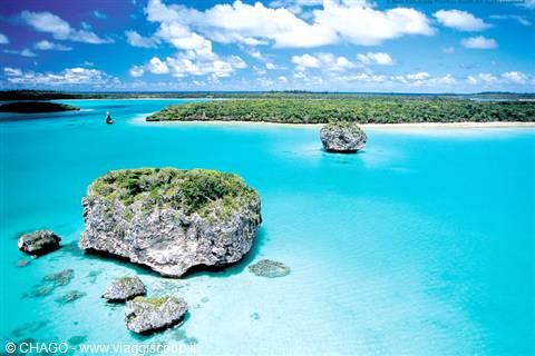 Green limestone rocks in turquoise lagoon, white sand beach and tropical trees