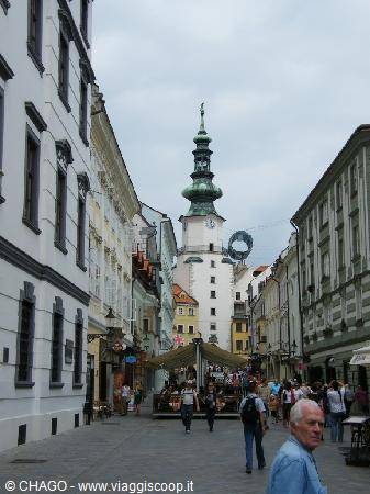 Pedestrians walking toward Michael's Tower on a busy Bratislava street