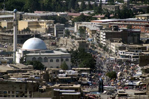 White dome and minaret above a crowded street market in Kabul