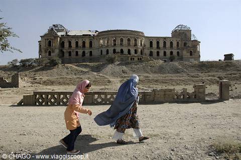 Women in burqas walk past the ruined Darul Aman Palace in Kabul