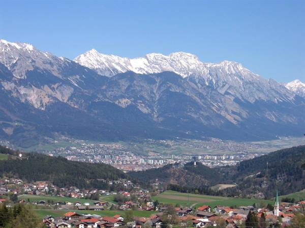 Village with red roofs and church steeple beneath the snow-capped Nordkette peaks, Innsbruck