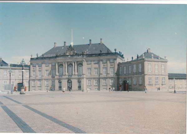 Tourists walk across the paved square in front of Amalienborg palace