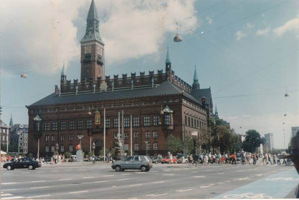 Copenhagen City Hall, red brick with clock tower, cars and pedestrians crossing the square