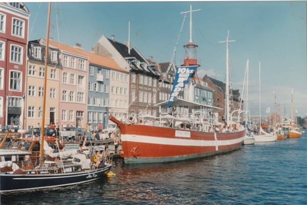 Nyhavn in Copenhagen: colorful townhouses, moored boats, flags in the wind